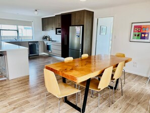 Una cocina moderna con armarios de madera oscura, electrodomésticos de acero inoxidable y una mesa de comedor de madera con cuatro sillas.