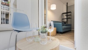 A modern living room with a round wooden table, a blue chair, and a sofa. - EASYLIFE – Your ideal space in Milan (Milano)