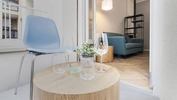 Ein modernes Wohnzimmer mit einem runden Holztisch, einem blauen Sessel und einer Couch.