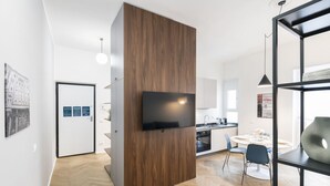 A modern kitchen with a built-in TV, wooden paneling, and a dining area with a round table and chairs. - EASYLIFE – Your ideal space in Milan (Milano)