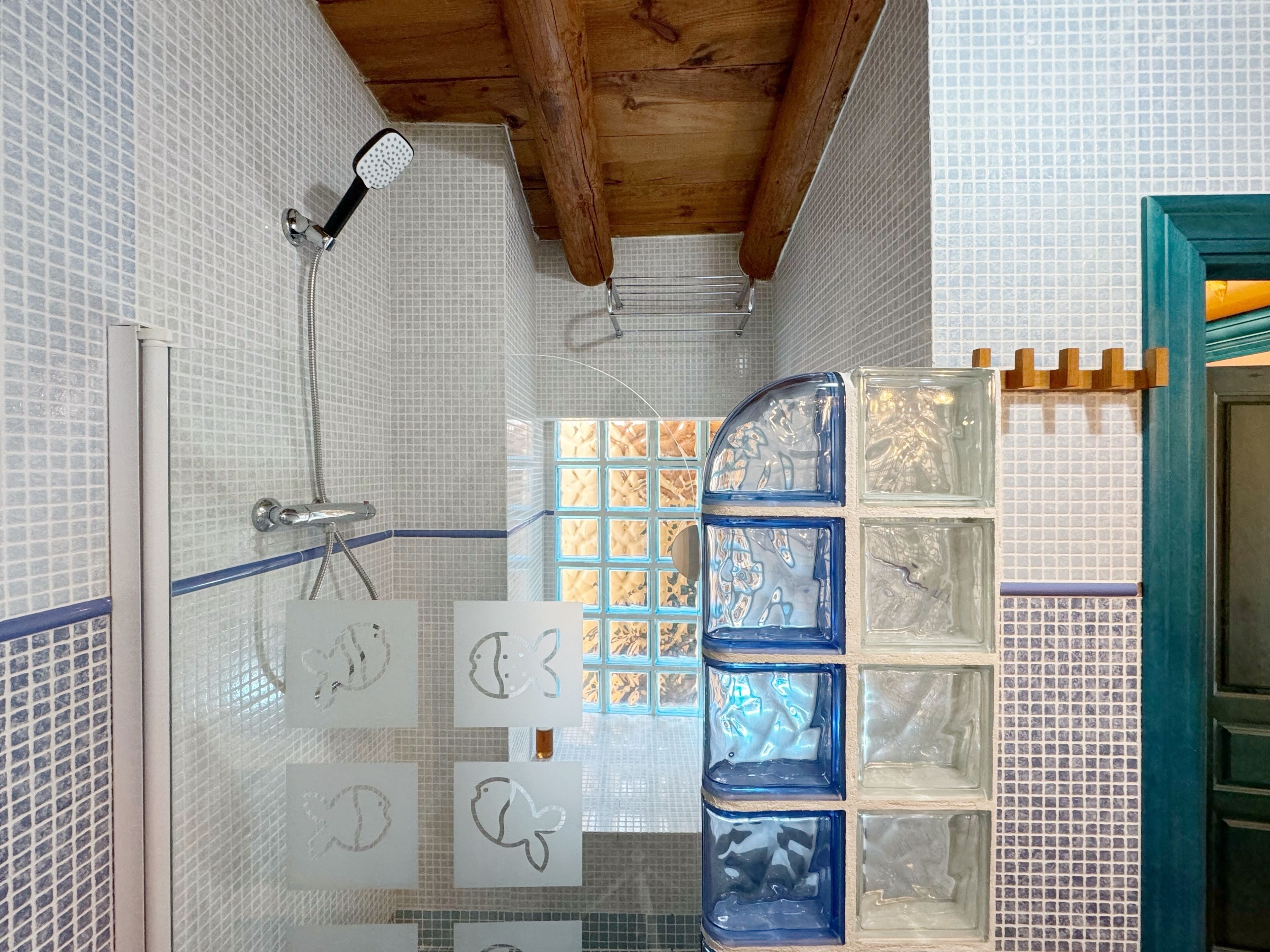 Un espace douche doté d’une porte en verre, de murs carrelés et d’un plafond en bois.