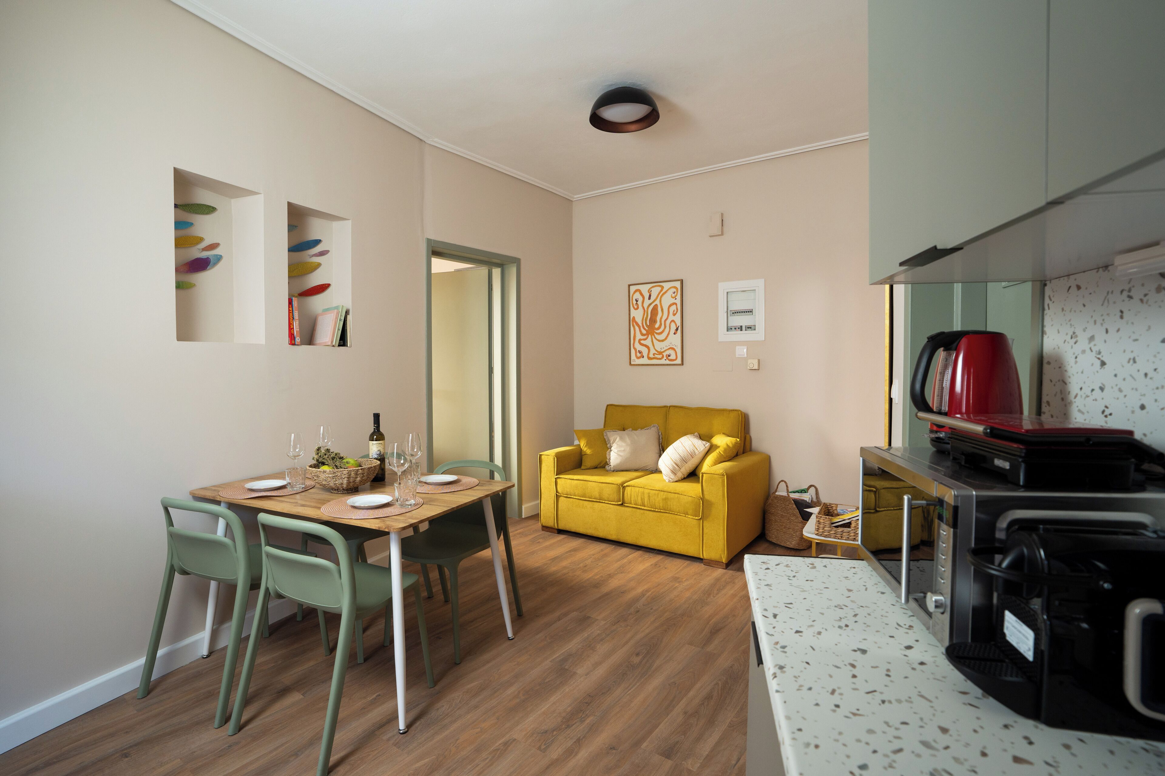 A compact living space with a dining area, a yellow sofa, and a kitchenette.