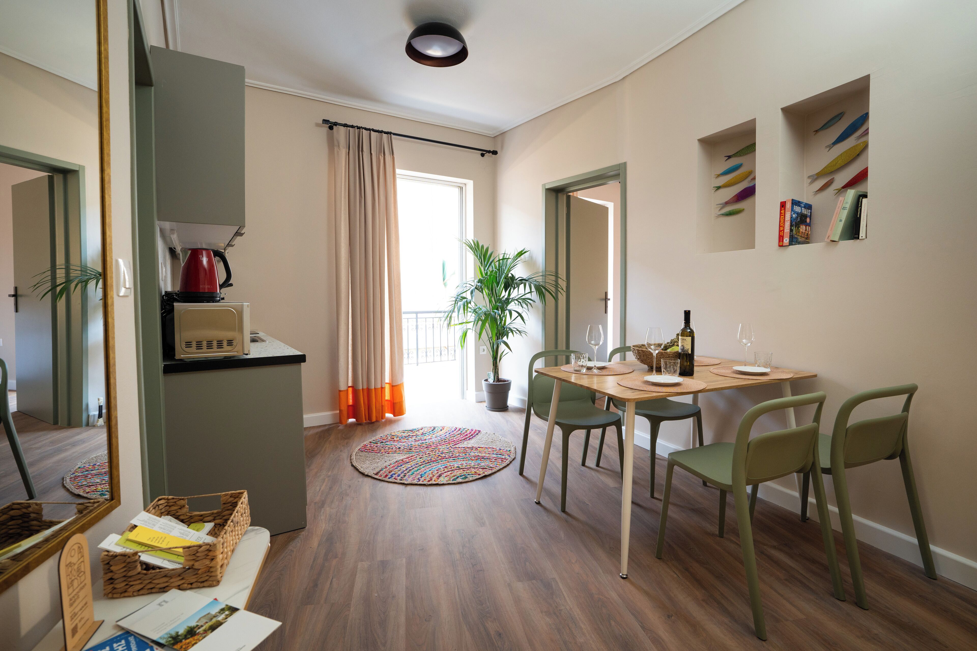 A modern living room with a dining area, a coffee machine, a potted plant, and a view of the outside.