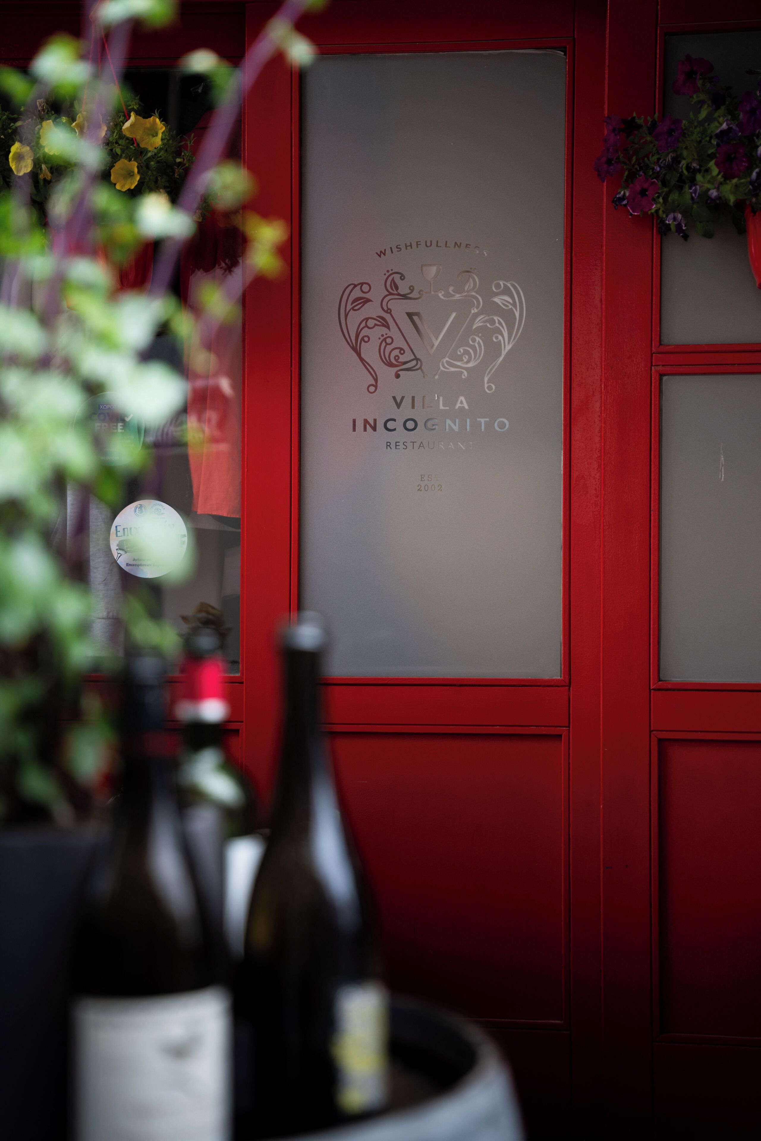 A red wall with a frosted glass window displaying a logo and text for 'Villa Cognito Restaurant'.