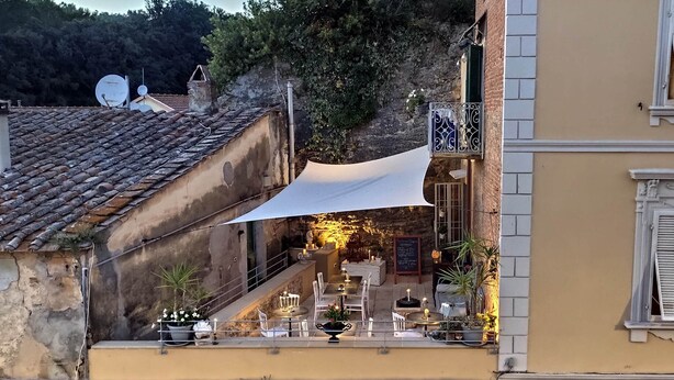 A terrace with outdoor seating, a stone wall, and a decorative balcony railing. - Residenza d'Epoca CAVALIERE (Bibbona)
