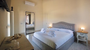 A bedroom with a large bed, bedside tables, a mirror, and a radiator. - Residenza d'Epoca CAVALIERE (Bibbona)