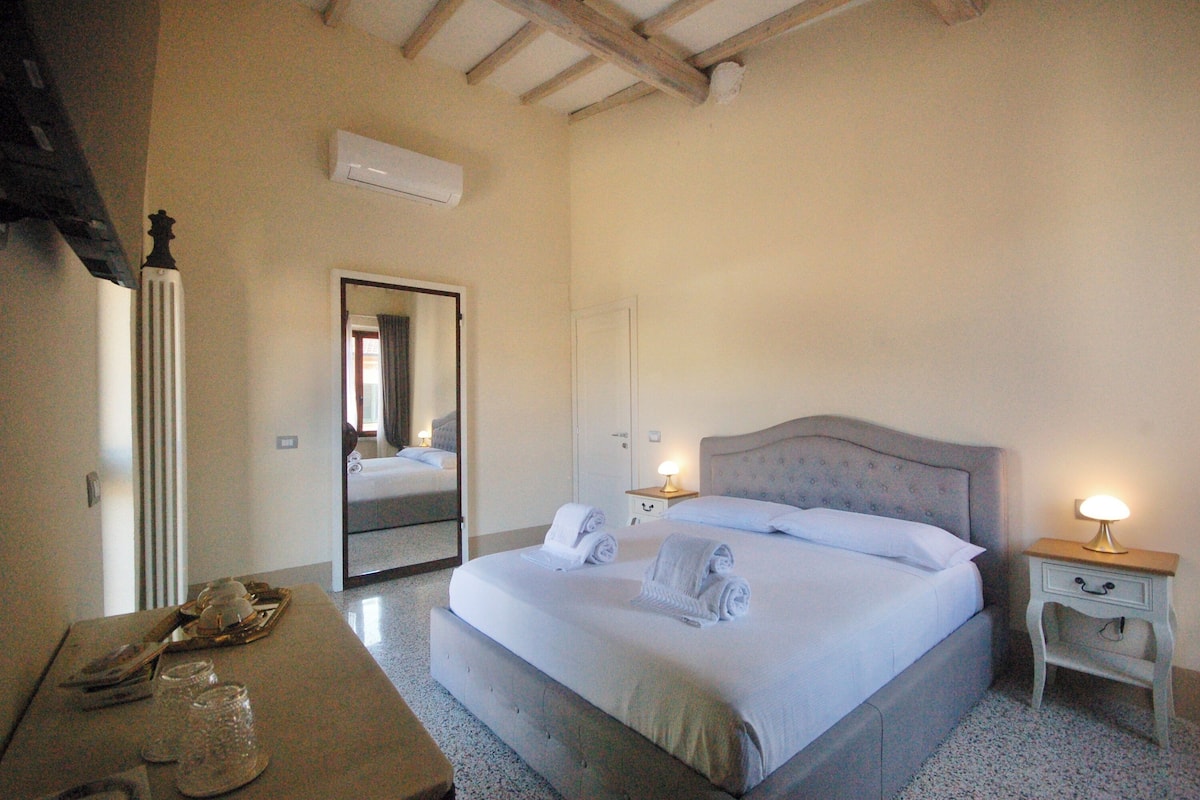 A bedroom with a large bed, bedside tables, a mirror, and a radiator.