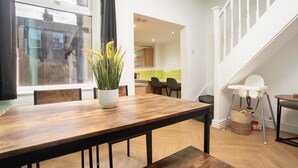 A modern kitchen with wooden cabinets, a dining table with chairs, and a view of the outside through a window. - Free Parking | Near Aintree Racecourse & Anfield | Ideal for Contractors & Families (Liverpool)