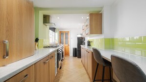 A modern kitchen with wooden cabinets, a granite countertop, and a view to the dining area. - Free Parking | Near Aintree Racecourse & Anfield | Ideal for Contractors & Families (Liverpool)