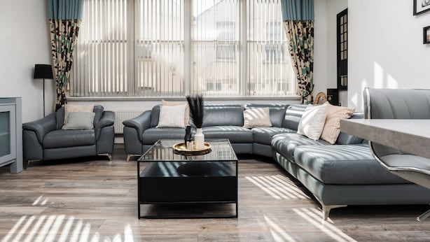 Una sala de estar moderna con un sofá modular, una mesa de centro de vidrio y un televisor a la izquierda.