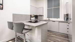 Una cocina moderna con una isla central, taburetes de bar y un ventanal con un diseño texturizado.