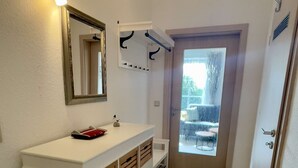 Ein Badezimmer mit weißem Waschtisch, einem Spiegel, einem Handtuchhalter und einer Tür, die auf einen Balkon führt.