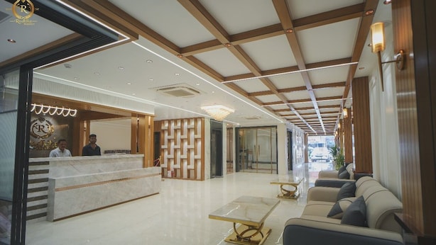 A hotel lobby with a reception desk, seating area, and a modern chandelier. - Hotel Radhika Regency (Balangir)