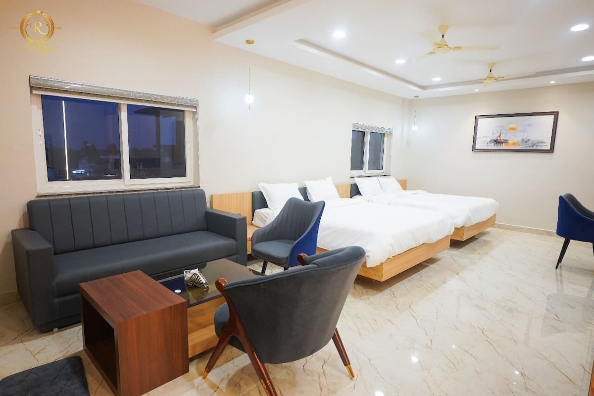 A modern hotel room with a sofa, a bed, a chair, and a small table.