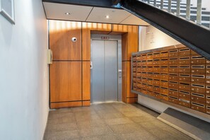 An elevator with a digital display and a mailbox wall with numbered slots. - Cosy CBD Loft Walk to Dining+Shopping Zodiak Stays (Auckland)