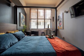 A bedroom with a bed, a window with blinds, a small table with cups, and a TV on the wall. - Cosy CBD Loft Walk to Dining+Shopping Zodiak Stays (Auckland)