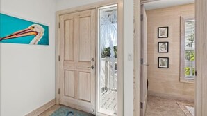Un pasillo con una puerta de madera, una puerta de cristal y una pared decorada con cuadros.