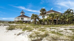 A coastal building with a lighthouse, surrounded by palm trees and sandy terrain. - 390 Gulf - Beachfront, 4 bed - 4 bath Private Pool - Dog Friendly! (Boca Grande)