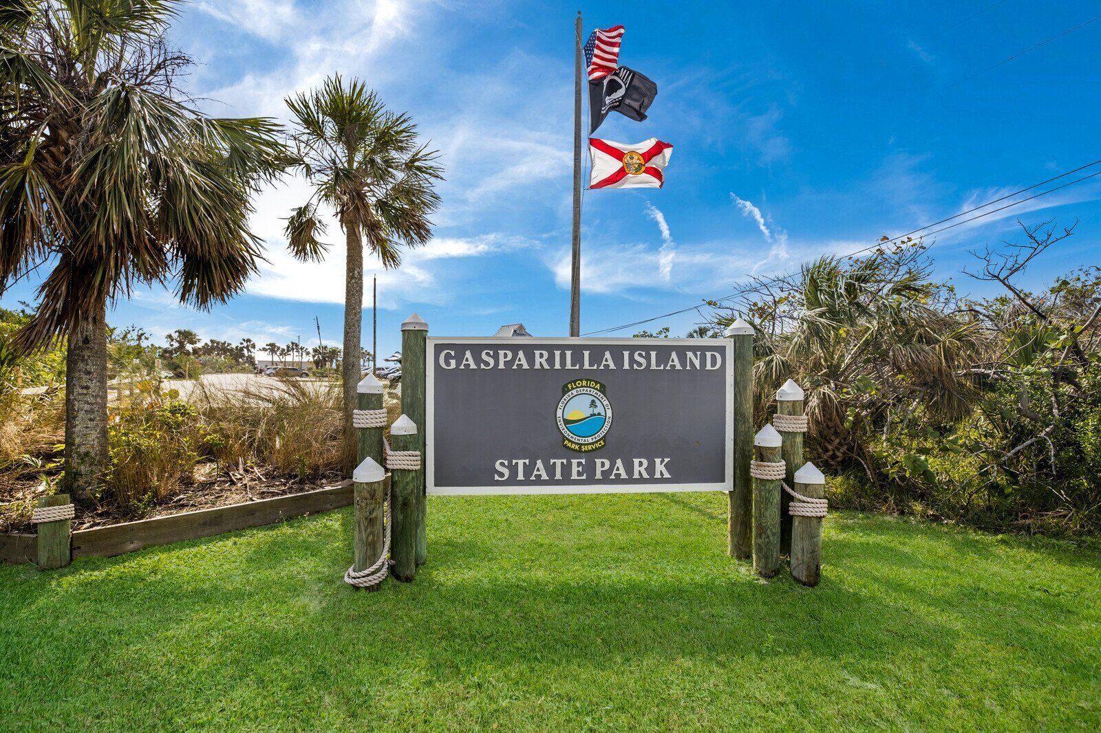 Skilt for Gasparilla Island State Park med et flagstang, hvor der er hejst det amerikanske flag og Florida's flag.