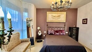Une chambre à coucher avec un grand lit, un lustre, un canapé et une commode.