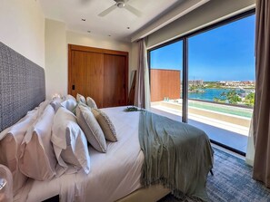 A bedroom with a large bed, a wooden wardrobe, and a view of a pool and cityscape. - Spectacular Marina Penthouse w private rooftop (Punta Cana)