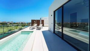A modern outdoor pool area with a clear view of the ocean and a cityscape in the background. - Spectacular Marina Penthouse w private rooftop (Punta Cana)