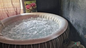 A hot tub with a control panel, surrounded by a dark wall and a window with a curtain. - Stay in béarnais country (Baigts-de-Béarn)