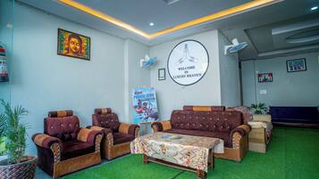 A lobby with a sofa set, a reception desk, a wall-mounted welcome sign, and a poster.