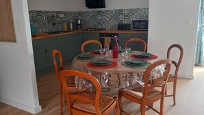A dining area with a round table set for four, surrounded by wooden chairs. - Maison la Tourterelle in Auvergne (Champs)