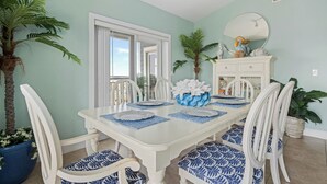Ein Esszimmer mit einem weißen Tisch, gedeckt für vier Personen, umgeben von weißen Stühlen mit blauen Mustern.