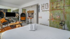 A modern hotel room with a large bed, a television, a bicycle, and a wall with the words "HO HO HO LIFE MADE".