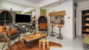 A modern living room with a large flat-screen TV, a wooden coffee table, a globe lamp, a leather sofa, and a bicycle in the background.