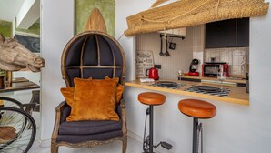 A modern kitchen with a bar area, a unique chair, and a bicycle.
