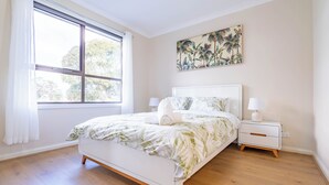 A bedroom with a bed, nightstands, a window, and a wall art piece. - Stylish, modern and secure family home! (Heidelberg West)
