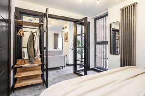 Una camera da letto moderna con un letto, un portascarpe in legno, un divano bianco e un'ampia finestra.