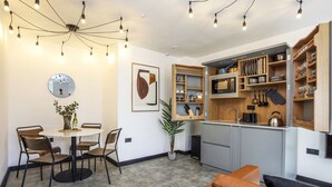 A modern kitchen with built-in appliances, a dining area with a round table and chairs, and a cozy seating area with a leather couch.