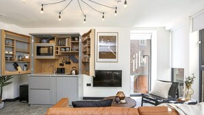 A modern kitchen with open shelving, a built-in microwave, and a large TV.