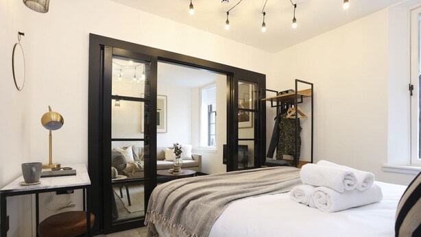 A modern bedroom with a large bed, a desk, and a wardrobe.