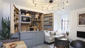 A compact kitchen with built-in appliances, a dining area with a wooden table, and a seating area with a sofa and armchairs.