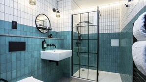 Un bagno con box doccia in vetro, lavandino bianco e water.