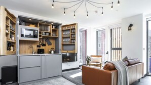 A modern kitchen with built-in appliances, a dining area with a sofa, and a large window providing a view of the city. - Laboratory Store: 2bed moments from Royal Mile (Edinburgh)