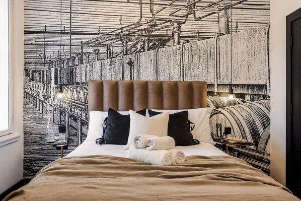 Une chambre d’hôtel avec un lit doté d’une tête de lit, d’oreillers et d’une serviette roulée.