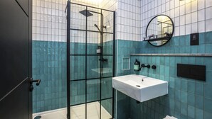 A modern bathroom with a glass shower enclosure, a white sink, and a mirror on the wall.