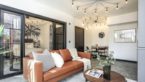 A modern living room with a leather sofa, a coffee table, and a dining area with chairs and a table.