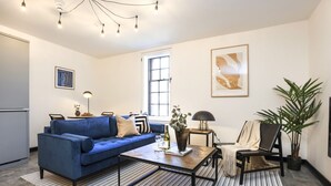 A modern living room with a blue sofa, a coffee table, a lamp, and a potted plant. - Engineering: Deluxe Studio w/City Views-2nd floor (Edinburgh)