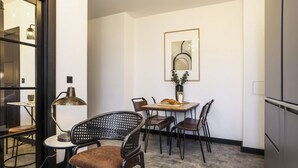 A modern dining area with a table set for two, surrounded by chairs. A lamp and a vase with greenery are on the table. - Locker Room:  Stylish 2bed w/City Views-3rd floor (Edinburgh)