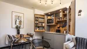 A compact kitchen with wooden cabinets, a microwave, and a sink. There is a dining area with a table and chairs. - Locker Room:  Stylish 2bed w/City Views-3rd floor (Edinburgh)
