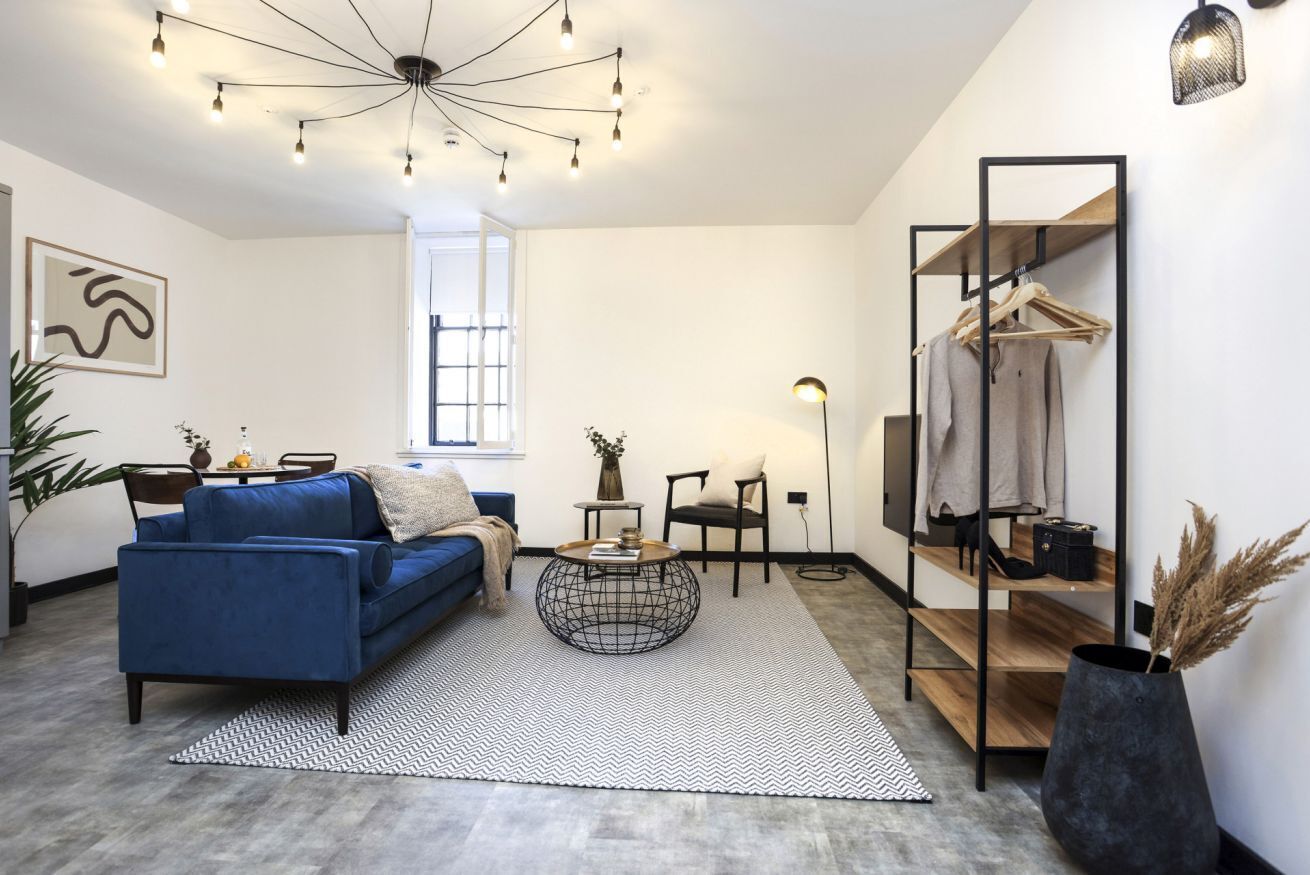 A modern living room with a blue sofa, a round coffee table, and a large window.