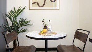 Una mesa redonda con tapa de mármol, dos sillas, una botella de licor, un vaso y un mantel tejido.