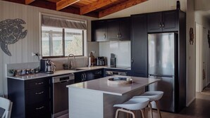 Une cuisine moderne avec des meubles de couleur sombre, des appareils électroménagers en acier inoxydable et un plafond en bois.